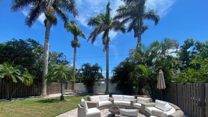 Un patio al aire libre con mobiliario de mimbre, palmeras y piso de ladrillo.