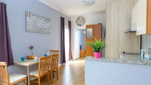 Une cuisine moderne avec des meubles en bois, un plan de travail en granit et un évier. On y trouve un coin repas avec une table et des chaises, ainsi qu’une grande fenêtre avec des rideaux.