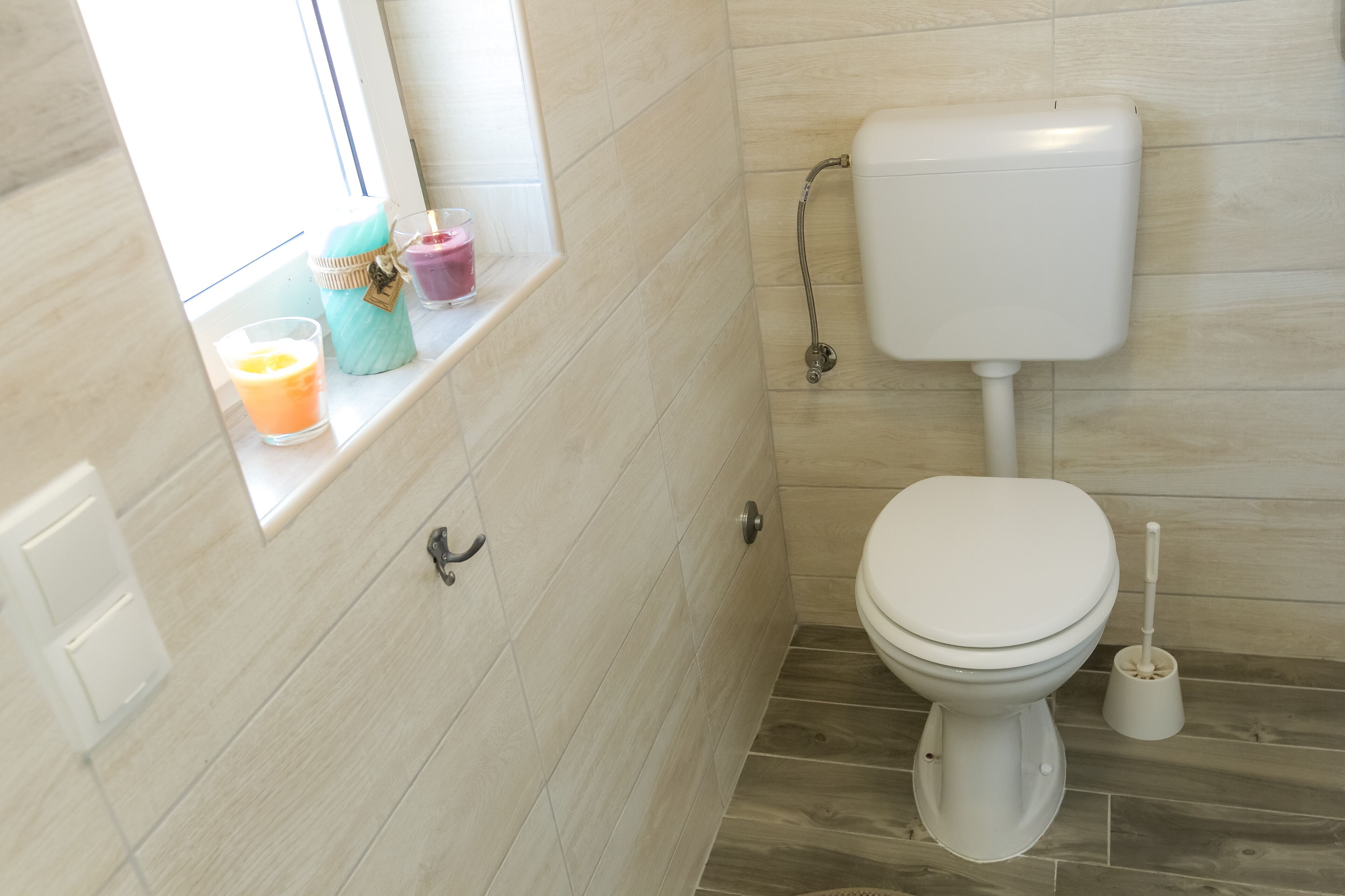 Ein Badezimmer mit Toilette, einem Fenster und einem Handlauf.