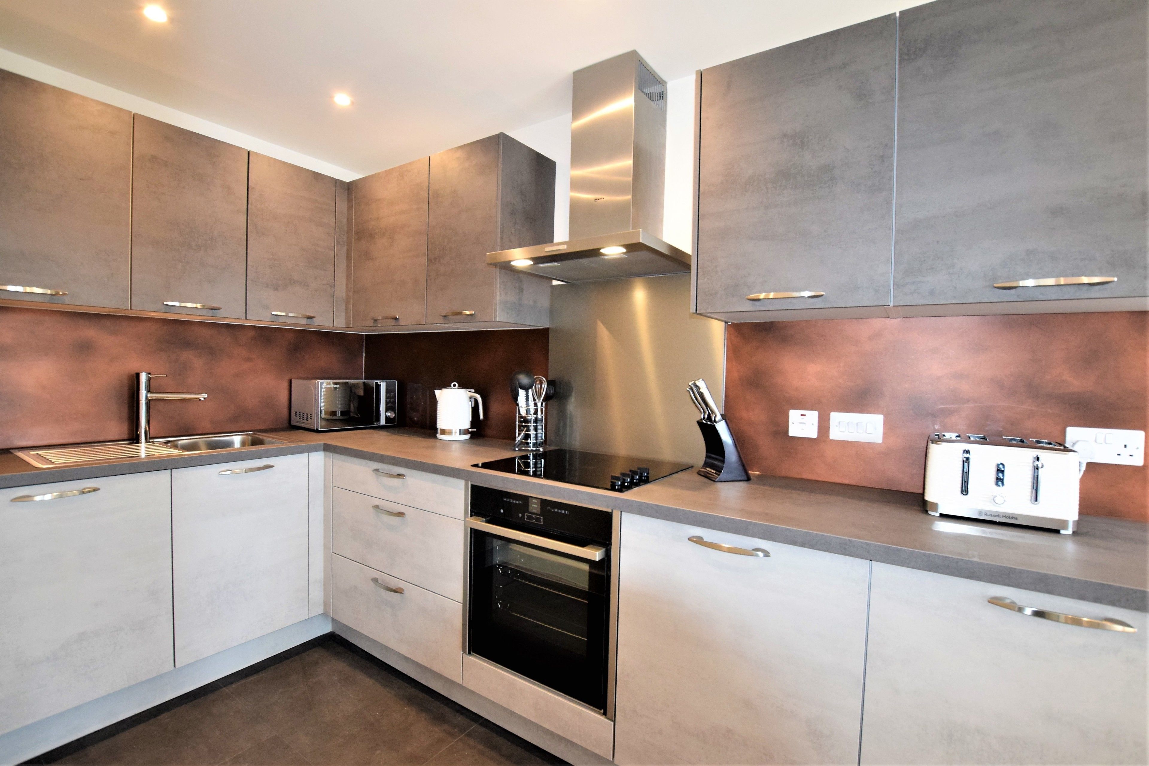 A modern kitchen with stainless steel appliances, a built-in oven, and a toaster.