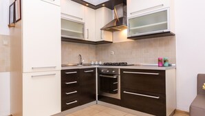 A kitchen with white and dark brown cabinets, a stainless steel range hood, and a tiled backsplash. - Apartment with Terrace and Partial Sea View and grill (Novalja)