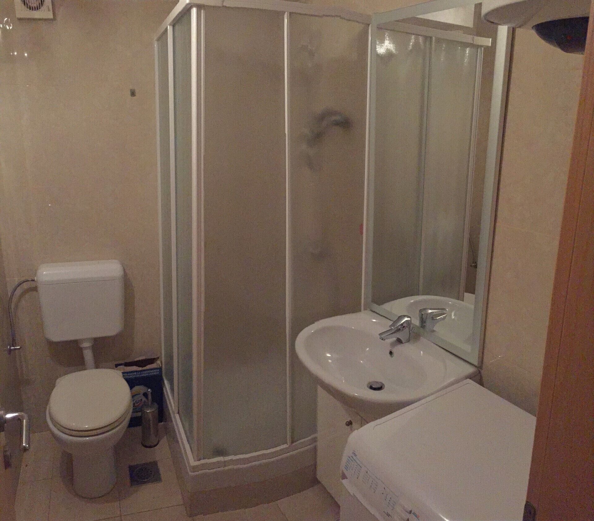 Un baño con inodoro, lavabo, cabina de ducha y espejo.