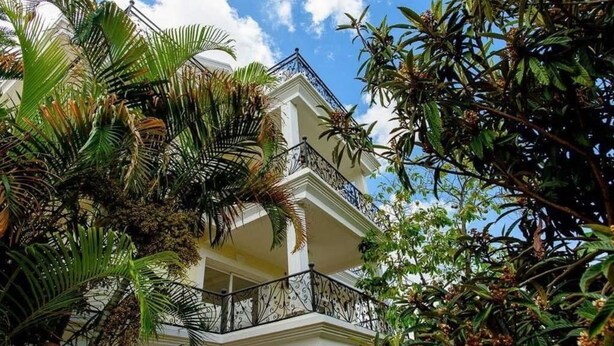 Un edificio de varios pisos con balcones, rodeado de exuberante vegetación tropical.