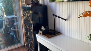 Quarto com escrivaninha, cadeira, televisão e objetos decorativos, incluindo um cacto e um abajur.