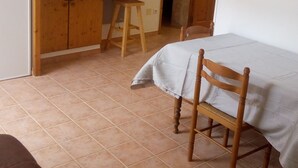 Een slaapkamer met een bed, een houten stoel, een bureau met een televisie, een klok en een plafondventilator.