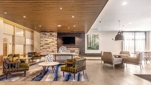 Un salón moderno con pared de piedra, techo de madera y mobiliario contemporáneo.