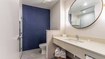 A modern bathroom with a white sink, mirror, and toilet.