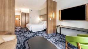 A hotel room with a bed, a desk, a chair, and a TV.