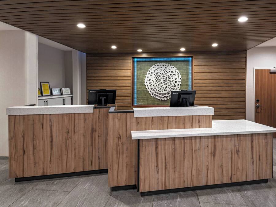 A reception area with wooden reception desks, a framed artwork on the wall, and a door to the right.