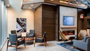 A modern living room with a fireplace, seating area, and a TV mounted on the wall. - TownePlace Suites by Marriott New York Long Island City/Manhattan View (Long Island City)