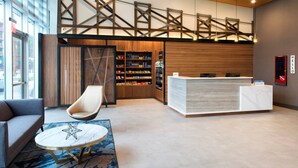 A modern reception area with a reception desk, seating, and a wooden wall with shelves. - TownePlace Suites by Marriott New York Long Island City/Manhattan View (Long Island City)