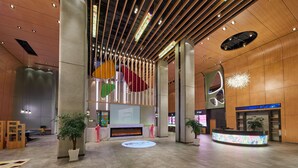 Una hall moderna con una reception, ampie colonne e un display digitale.