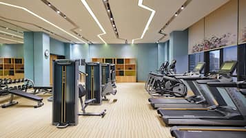 A modern gym with treadmills, weight machines, and dumbbells.