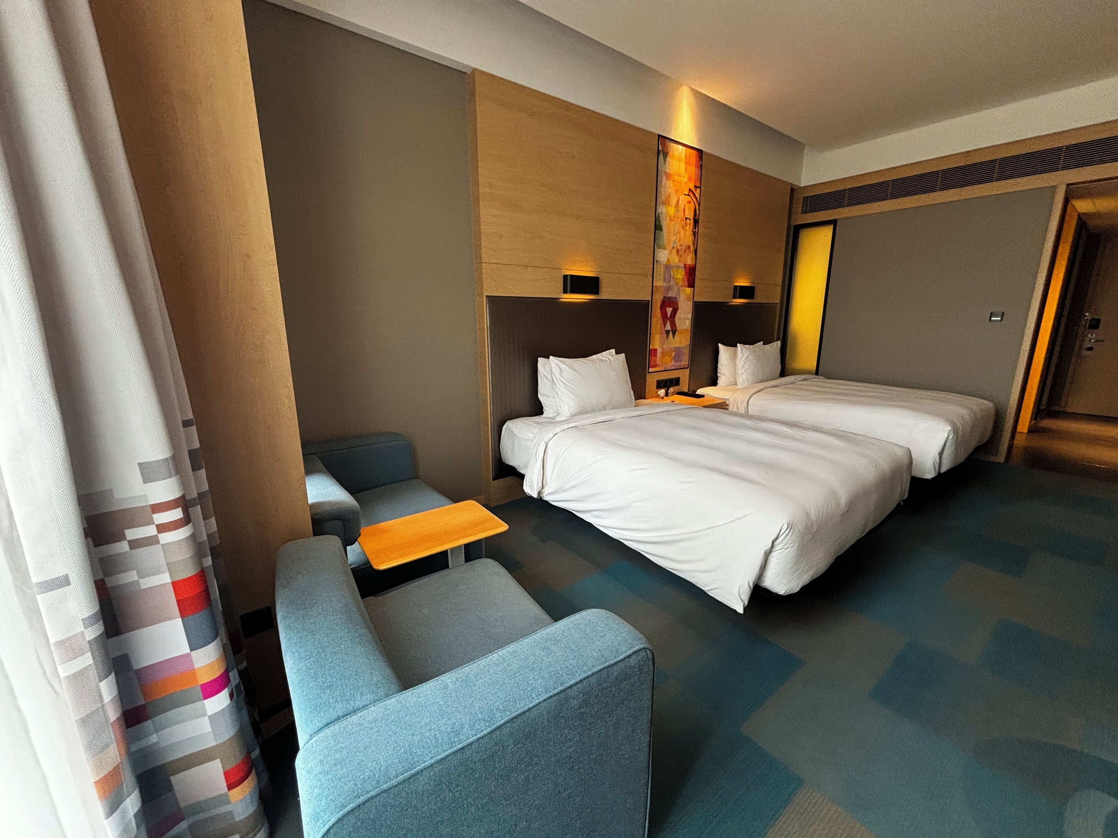 A hotel room with a bed, two bedside tables, a small sofa, and a desk.