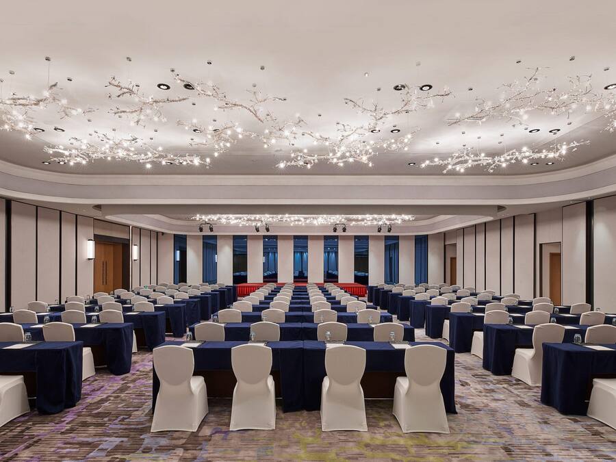 A conference room with rows of tables, chairs, and a stage at the front.