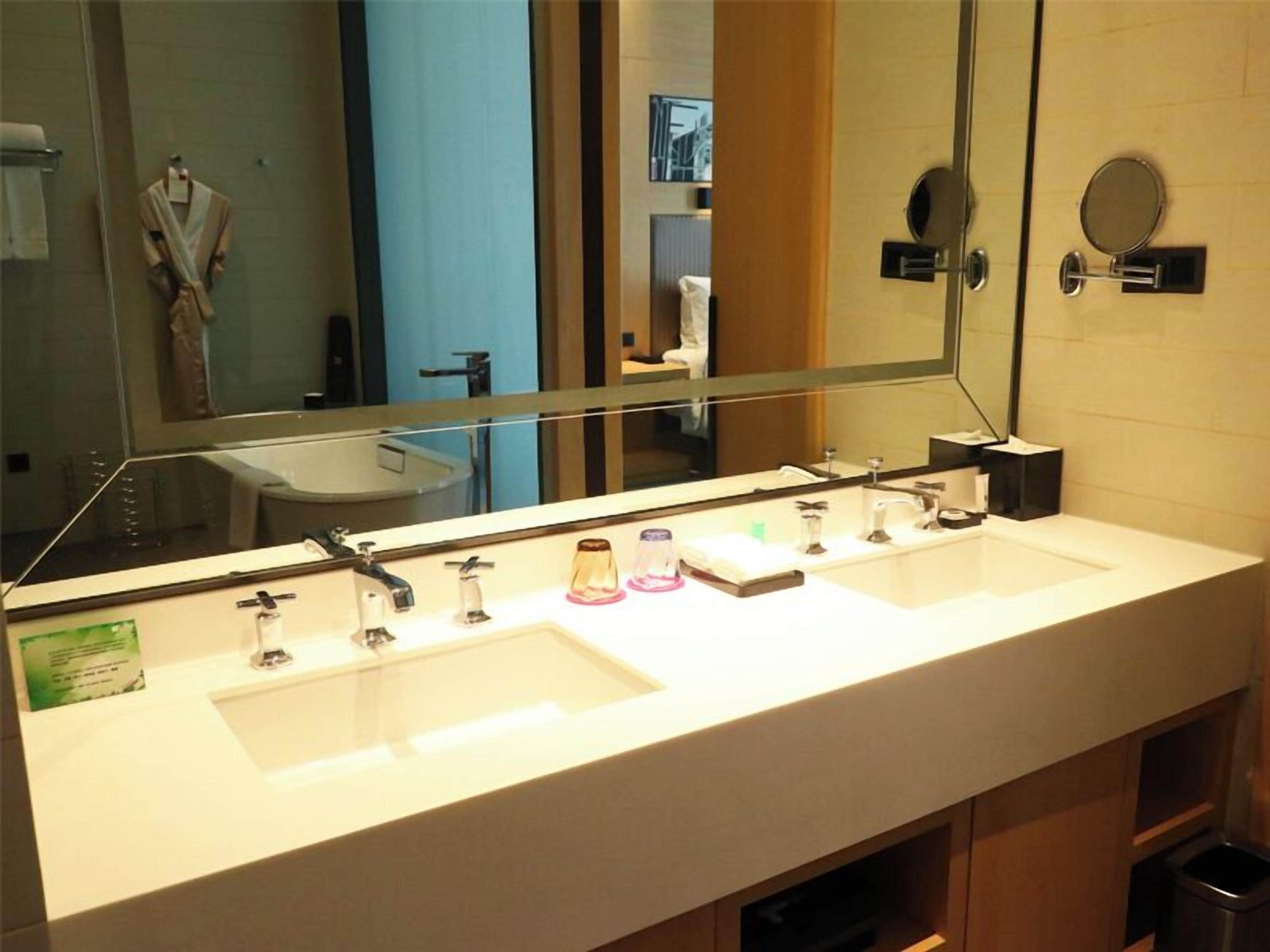 Une salle de bain d’hôtel avec deux lavabos, un grand miroir et un porte-serviettes.