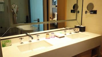 Une salle de bain d’hôtel avec deux lavabos, un grand miroir et un porte-serviettes.