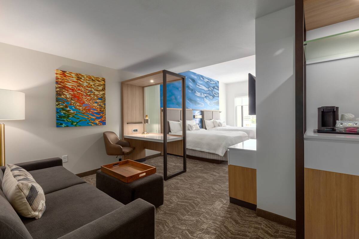 Habitación de hotel con sofá, escritorio, cama y un espejo grande.