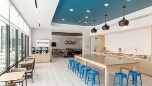 Un área de cocina moderna con una barra, taburetes azules y una isla grande.
