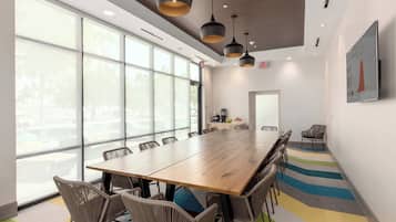 A conference room with a long wooden table, wicker chairs, and pendant lighting.