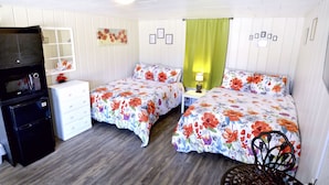 Un dormitorio con dos camas, un aparador, un microondas y una mesita de noche con una lámpara.