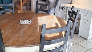 A dining area with a round wooden table, four chairs, a staircase, a TV, and a desk with a lamp. - La Maison de la Grève (Ouistreham)