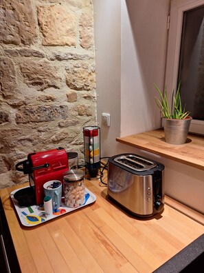 A kitchenette with a coffee maker, toaster, and a small potted plant on a wooden countertop. - La Maison de la Grève (Ouistreham)