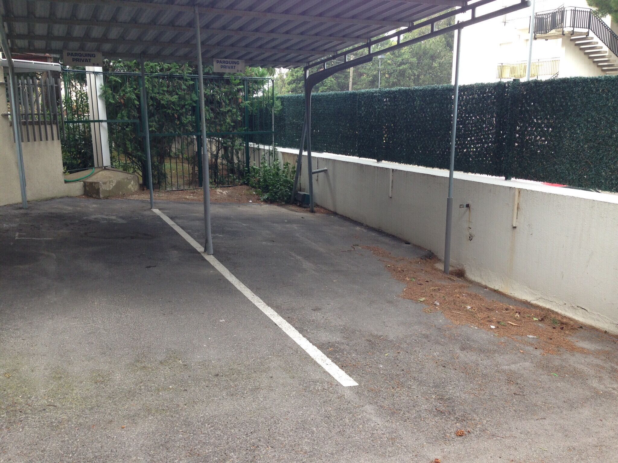 A covered parking area with a concrete floor and metal railings.