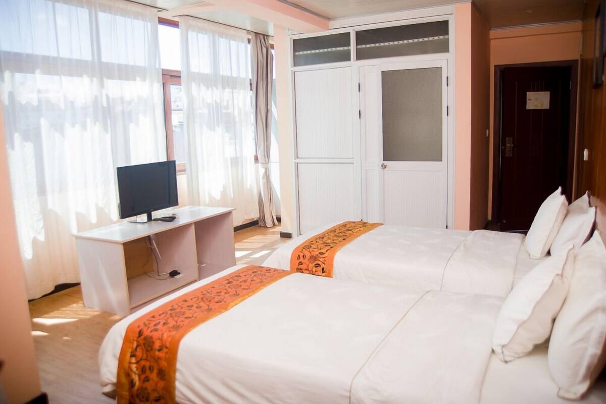 A hotel room with two beds, a desk with a computer, and a wardrobe.