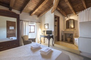 A bedroom with a wooden ceiling, a bed with towels, a desk, a chair, a television, and a bathroom with a sink and mirror. - Sa Bisbal - Turismo De Interior (Selva)