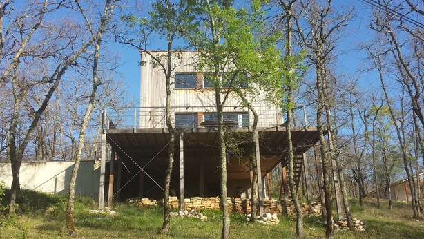 A rustic cabin with a wooden deck, surrounded by trees and a stone wall. - Modern wooden house with tree terrace and private heated pool (Luzech)