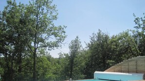 A swimming pool with a wooden deck and steps leading into it, surrounded by trees. - Modern wooden house with tree terrace and private heated pool (Luzech)