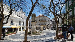 Une place publique pavée de pierres, agrémentée d’arbres et bordée de bâtiments historiques.