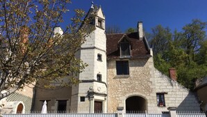 Un edificio de piedra con una torre, ventanas arqueadas y una cerca blanca.