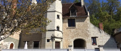 A stone building with a tower, arched windows, and a white fence.