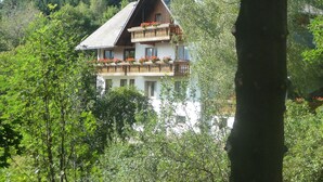 A multi-story building with balconies, surrounded by dense greenery. - Landhaus Valentin (Triberg im Schwarzwald)