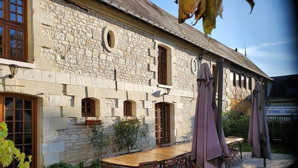 A stone building with a wooden deck, outdoor seating, and a pergola. - Pic Epeiche Gite (Lerné)