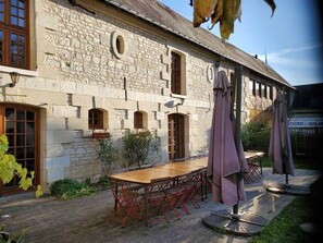 Ein Steinhaus mit einer Holzterrasse, Außenmöbeln und einer Pergola.