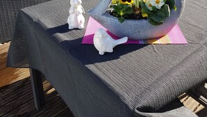 A patio table with a stone planter containing flowers and a rabbit figurine. - Beautiful apartment with large sun terrace - Apartment Elegance (Höheischweiler)