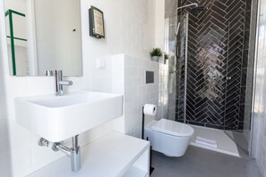 A modern bathroom with a white sink, toilet, and shower. - Alameda Exclusive House (Faro)