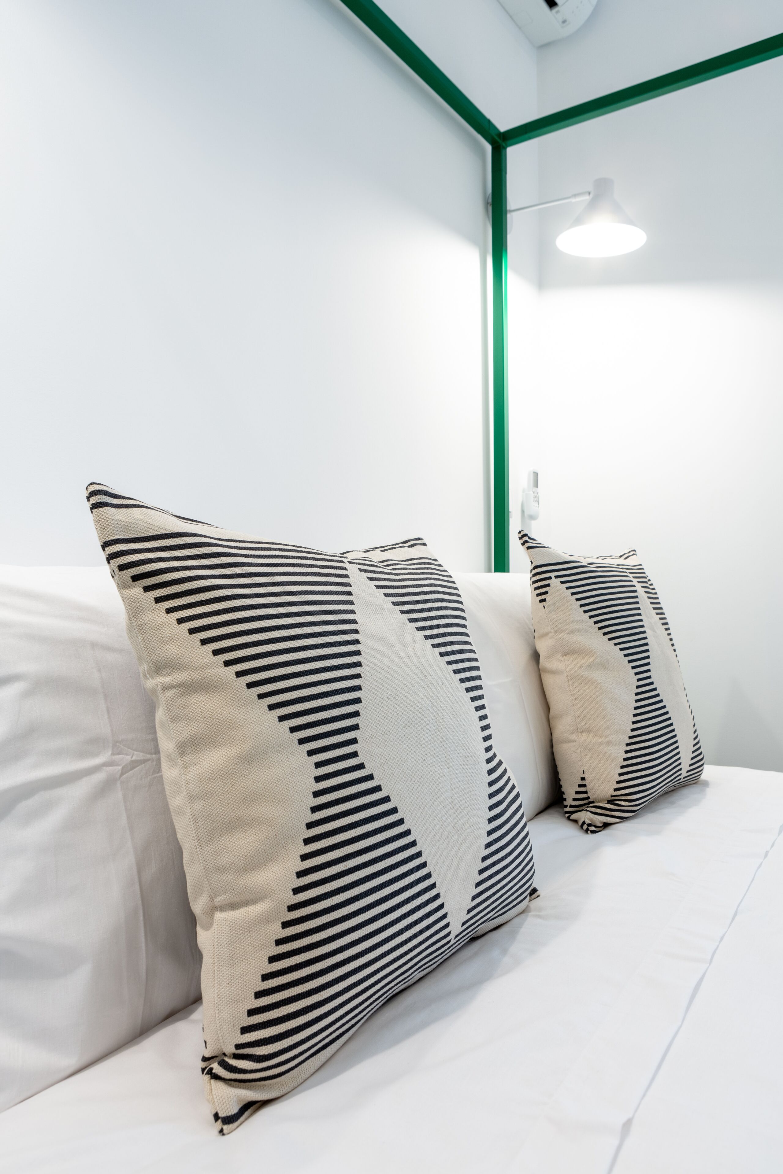 Una cama con ropa de cama blanca y almohadas a rayas.
