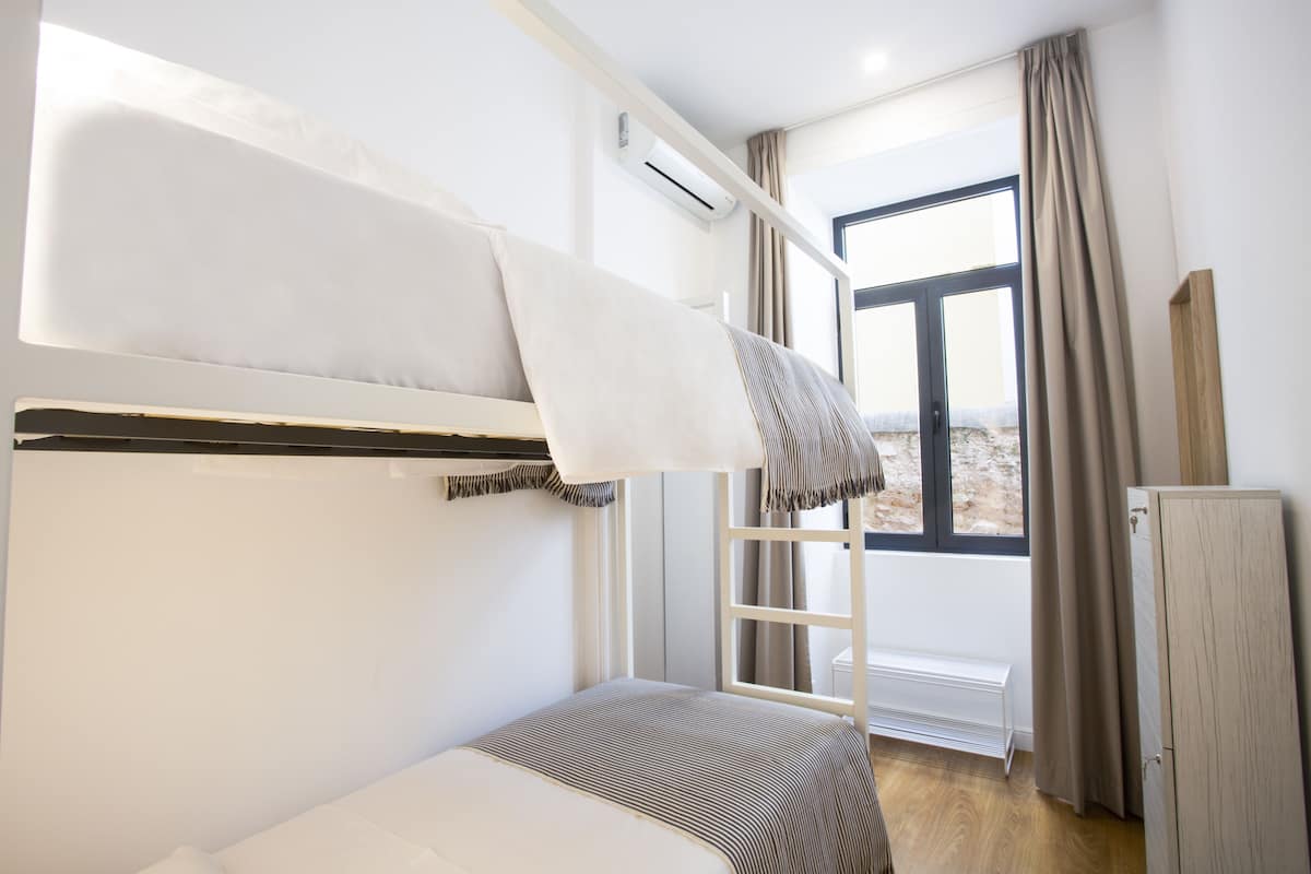 A bunk bed room with a window, a radiator, and a wardrobe.