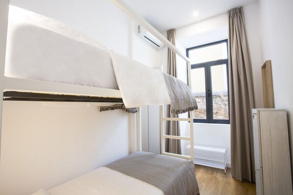 A bunk bed room with a window, a radiator, and a wardrobe. - Alameda Exclusive House (Faro)