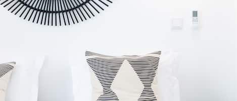 A modern bedroom with a circular wall decoration, striped pillows, a green side table, and a remote control.