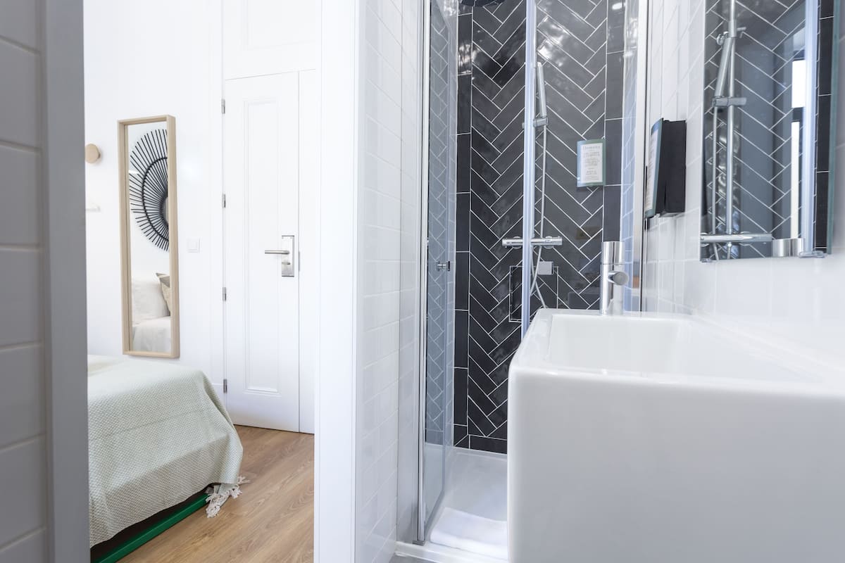 A modern bathroom with a large white sink, a glass shower enclosure, and a mirror.
