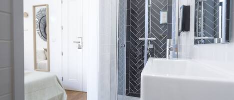 Un baño moderno con un lavamanos grande de color blanco, una cabina de ducha con mampara de vidrio y un espejo.