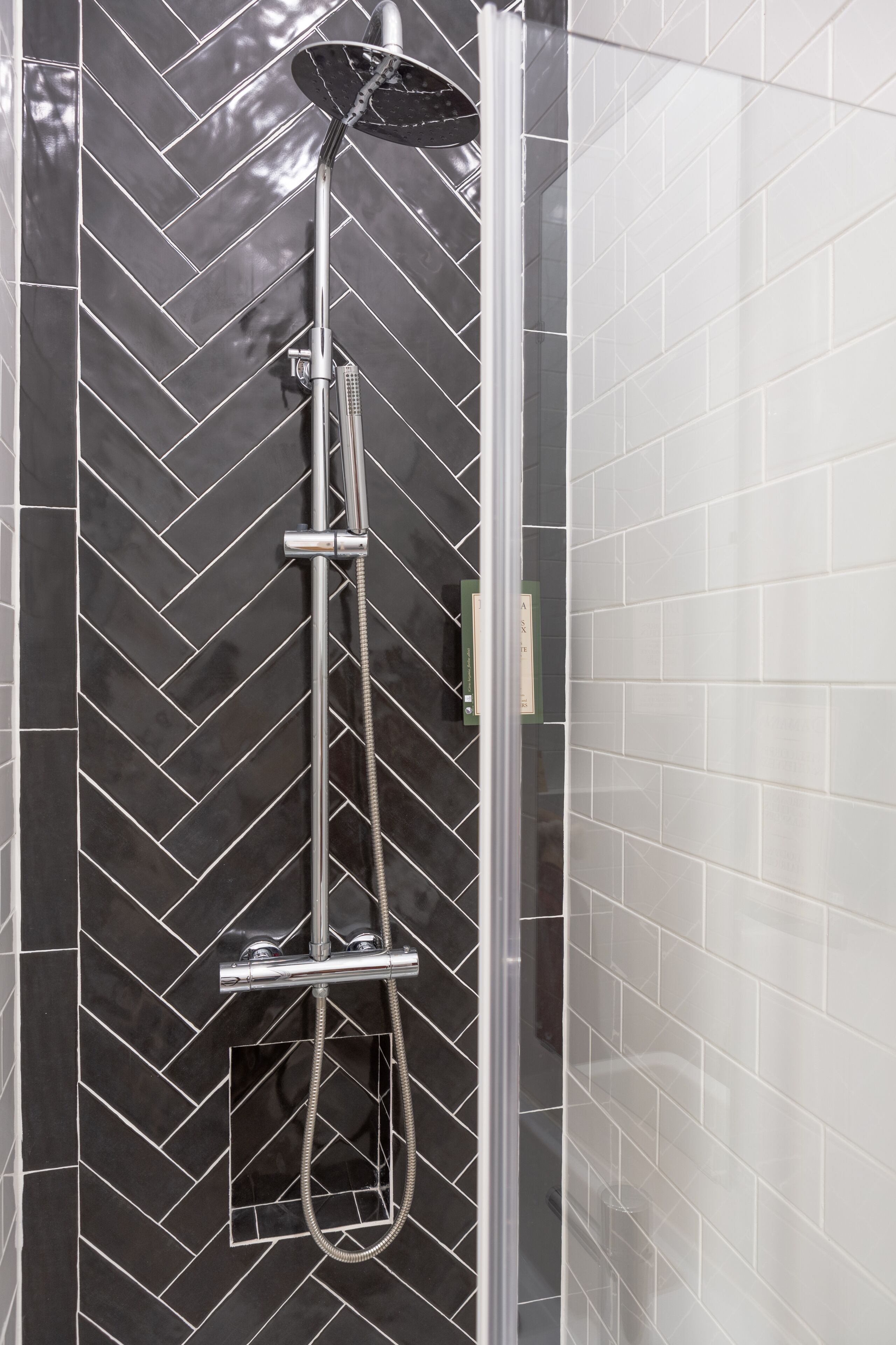 A shower with a modern design, featuring a rain showerhead and handheld showerhead.