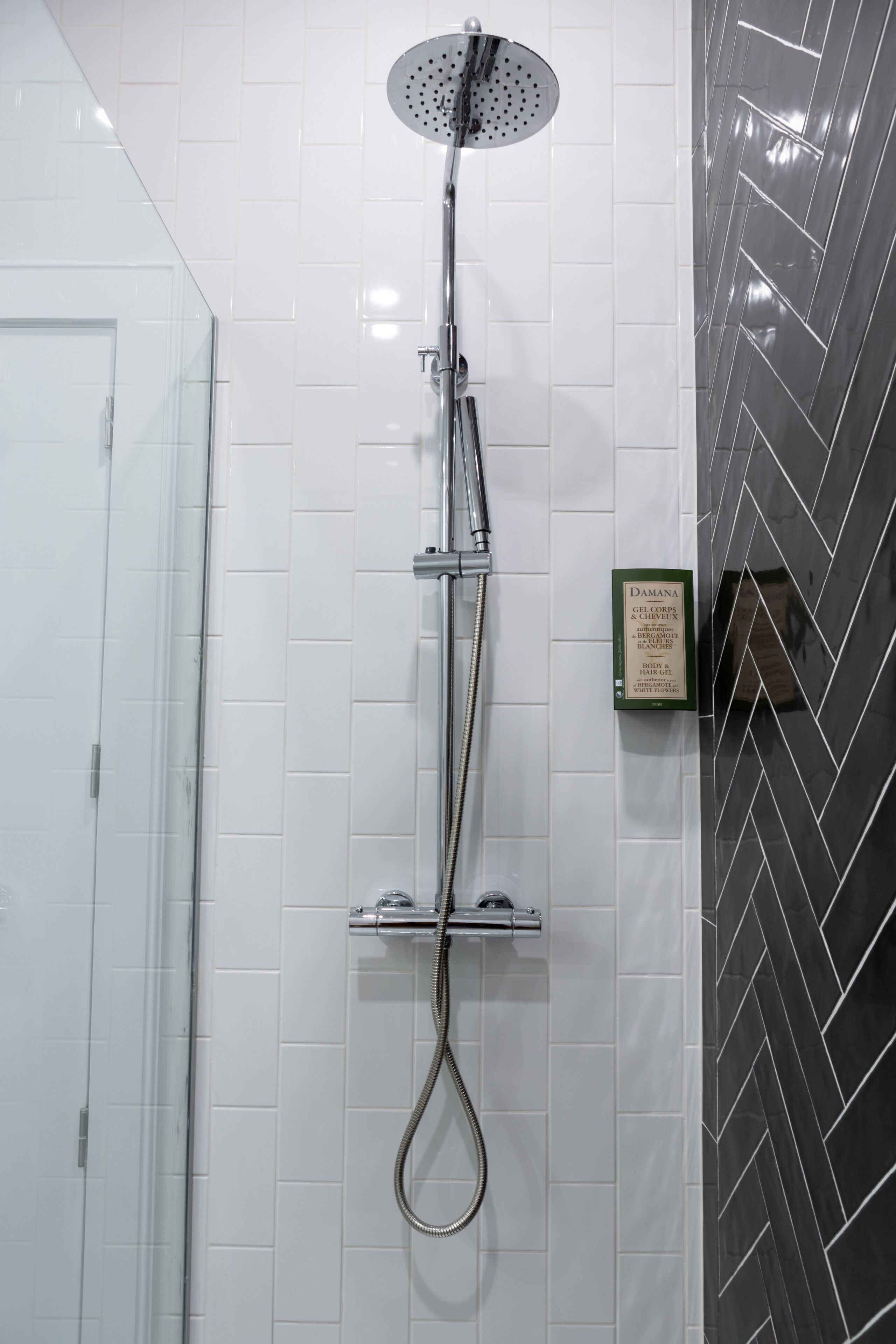 Una ducha con cabezal de ducha de mano y panel de control en la pared.
