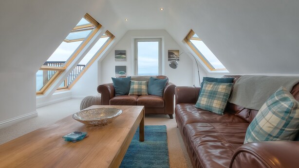 Ein Loft-Wohnzimmer mit einem braunen Ledersofa, einem Holztisch und einem großen Oberlicht.