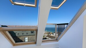 Ein Zimmer mit Dachfenstern und Meerblick.